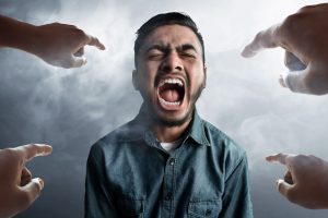 A powerful conceptual image of a man shouting in distress while being surrounded by multiple hands pointing accusingly at him. This photo powerfully illustrates the potential negative backlash and reputational damage that can occur from a poorly planned ad campaign, emphasizing the core message of the ASCI report that 'Right advice at ad planning stage can mitigate risks and build trust,' Published on December 02, 2021.
